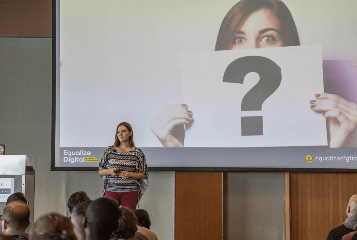 amber hinds standing on stage giving a presentation to a large group of people