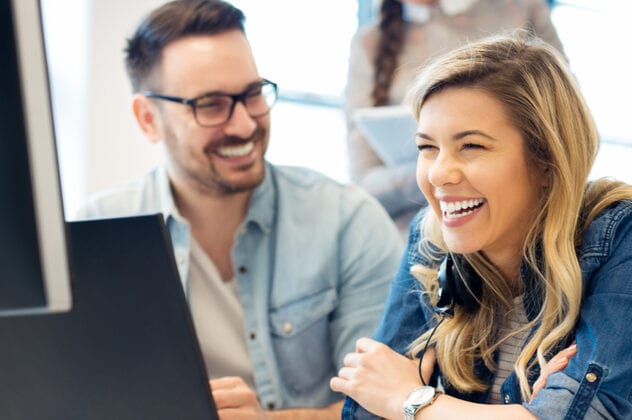 happy man and woman in office looking at computer