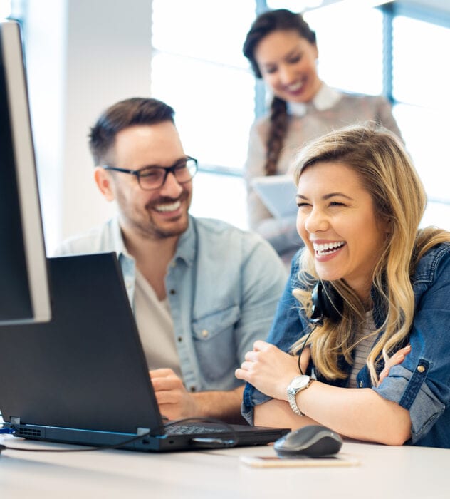 happy man and woman in office looking at computer