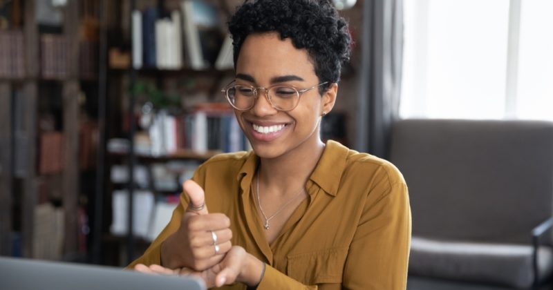 woman smiling in front of a computer signing the word help