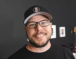 Smiling photo of Kyle with a black hat and beard