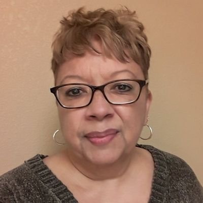 Headshot of Anita wearing glasses in a green sweater.