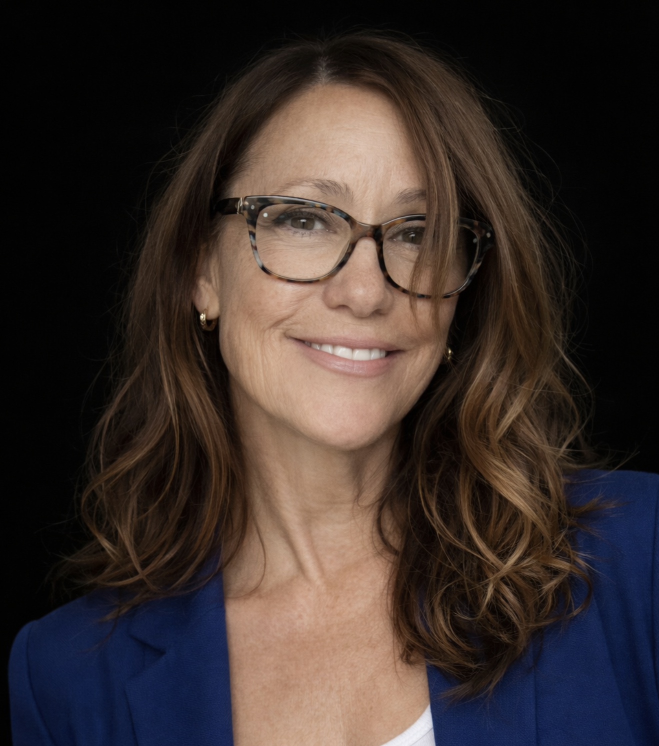 woman of a certain age with faint brun scars and medium length wavy brown hair with highlights
